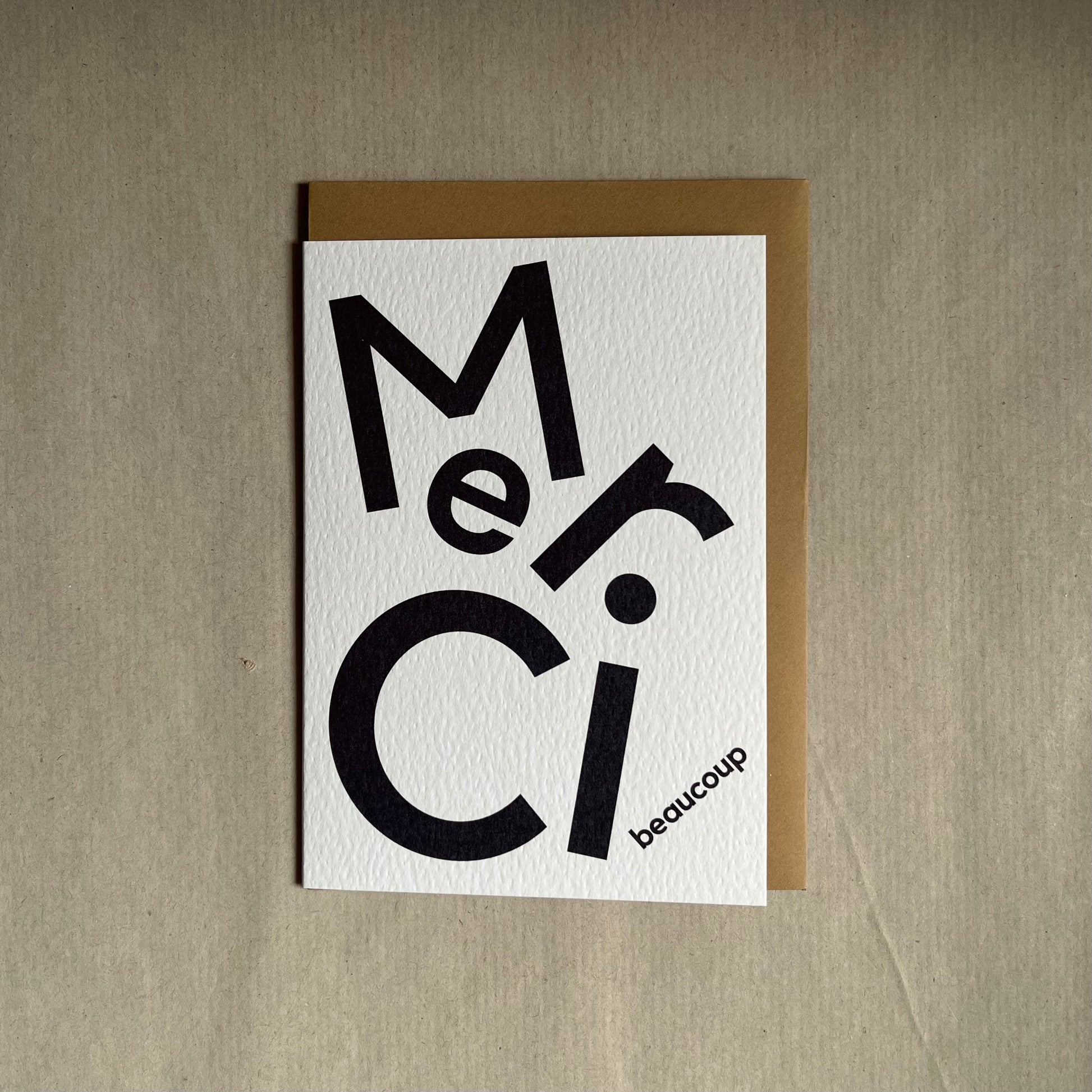 Thank you greeting card with 'Merci beaucoup' text on a beige background