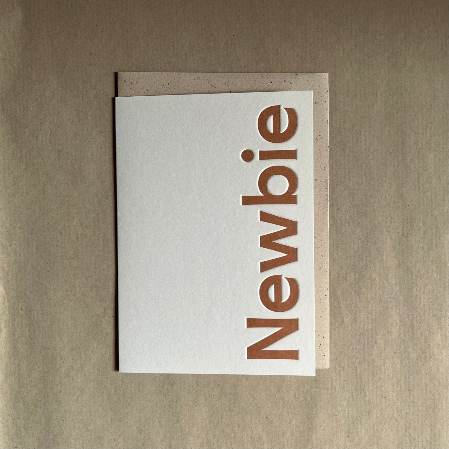 New baby greeting card on white card with 'Newbie' printed in text on right side.  