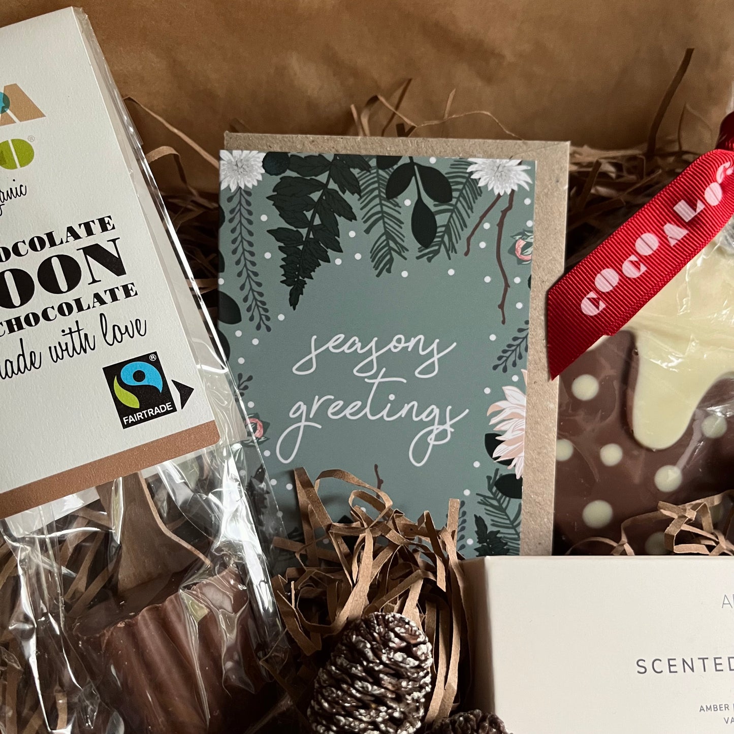 Relaxing winter-care gift box with hot chocolate spoon, chocolate christmas pudding, scented tea lights and mini greeting card.