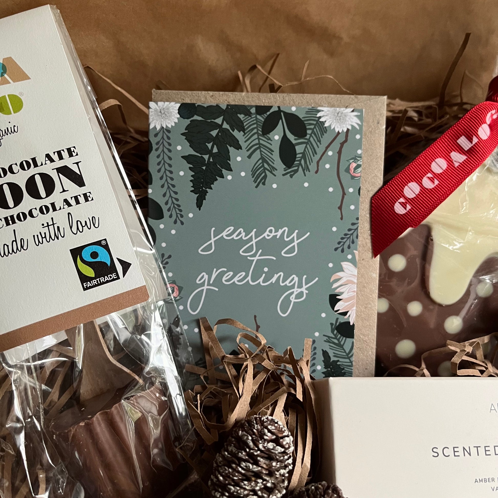 Relaxing winter-care gift box with hot chocolate spoon, chocolate christmas pudding, scented tea lights and mini greeting card.